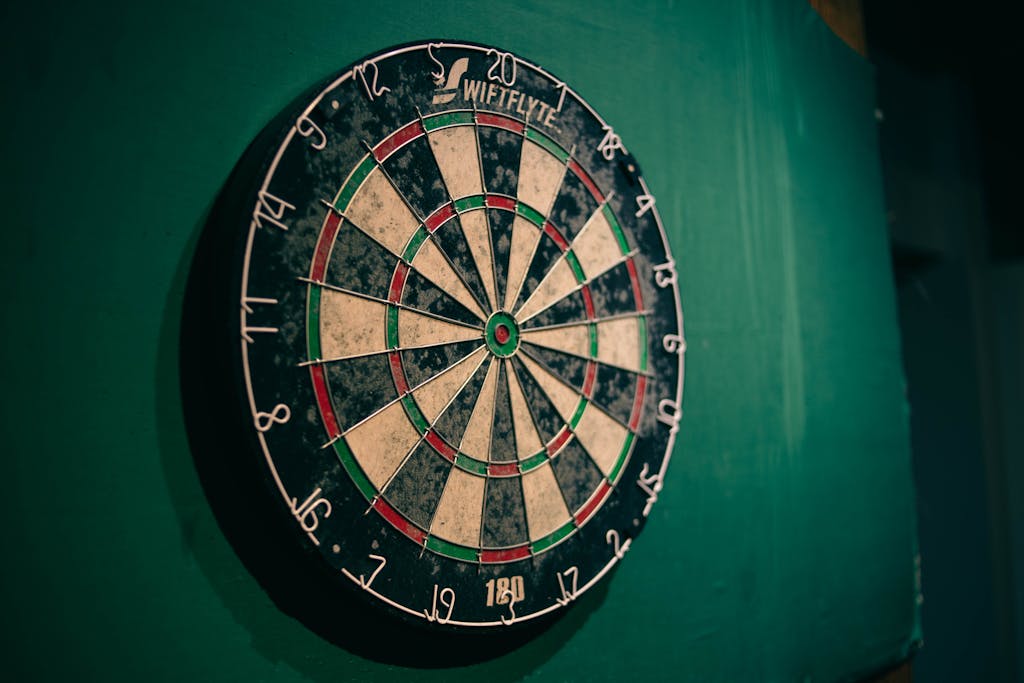 Worn dartboard on a green wall indoors, perfect for sports entertainment themes.