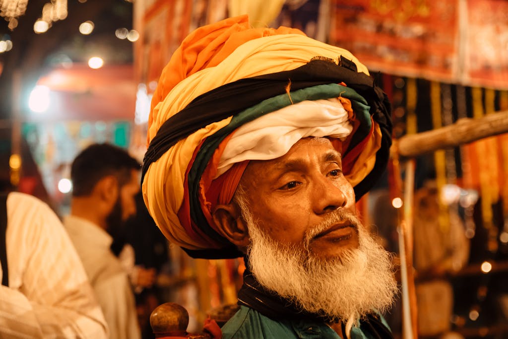 Close-up of a man wearing a colorful traditional turban in a lively Lahore market.